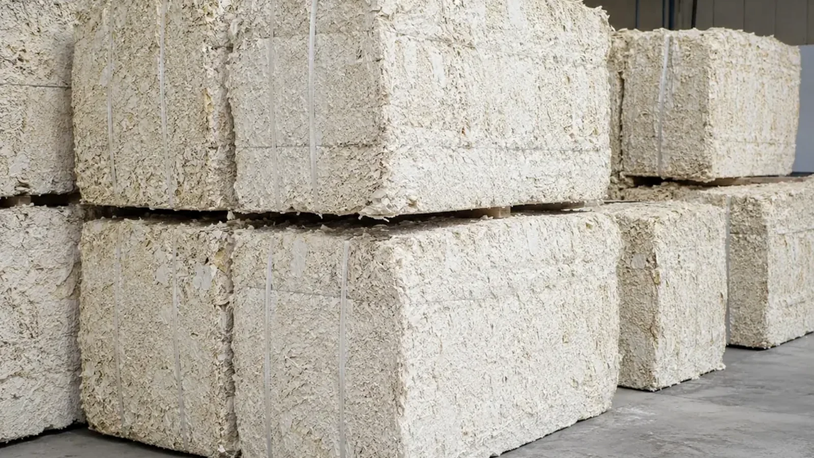Dense bales of mechanically opened recovered cardboard fiber prepared for storage or transport