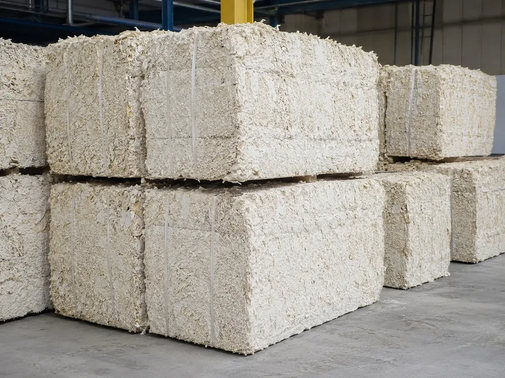 Dense bales of mechanically opened recovered fiber from a cardboard recycling line